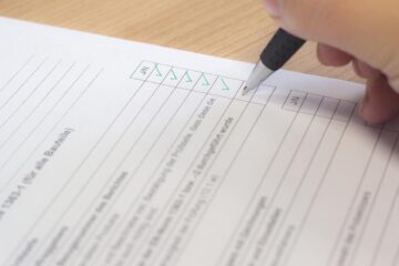 Pessoa preenchendo checklist para vistoria de imóvel com caneta sobre mesa